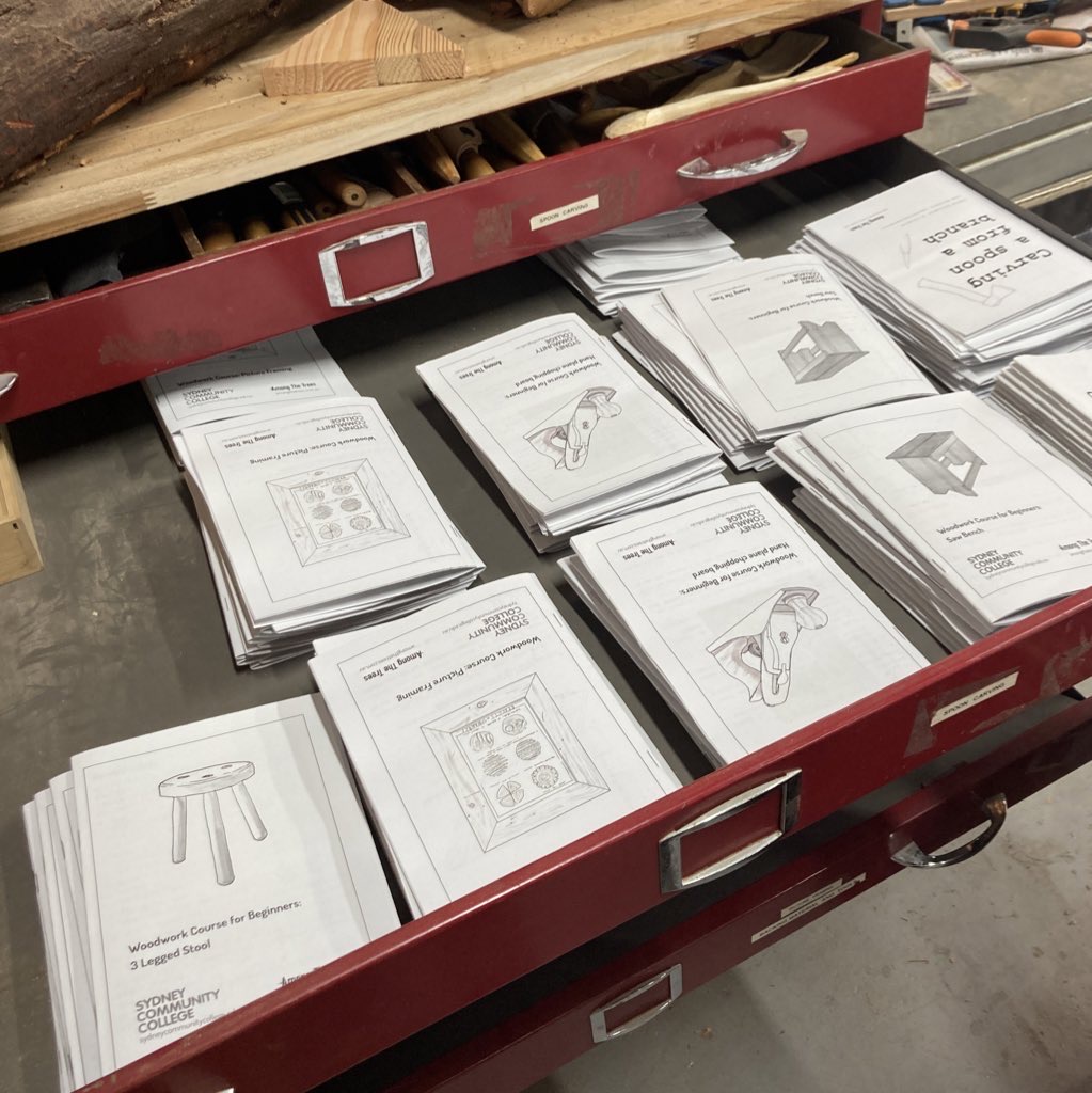 A drawer of folded course booklets with cover illustrations